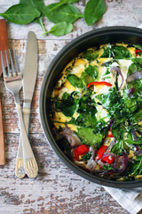 Selective focus. Healthy homemade omelet with spinach and vegetables. Spinach omelet in a pan. Cooking healthy food at home.