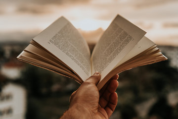 Man reading a book on the balcony during sunset. The sun is shining. Book Fair

