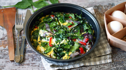 Selective focus. Healthy homemade omelet with spinach and vegetables. Spinach omelet in a pan. Cooking healthy food at home.