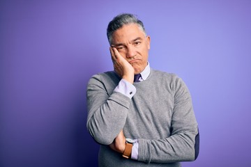 Middle age handsome grey-haired man wearing elegant sweater over purple background thinking looking tired and bored with depression problems with crossed arms.