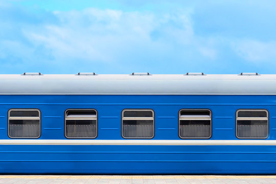 Blue passenger railway wagon on the platform, blue sky in the background