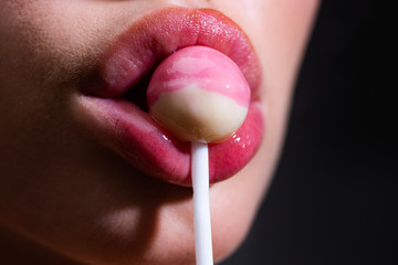 Close up lips sucking a lolipop, lollypop. Woman with lollipop in mouth. Red lips, sweats lolly pop.