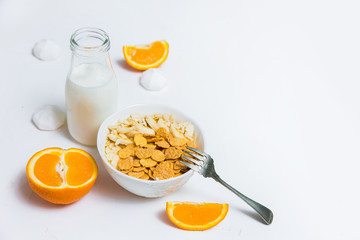 A delicious diet breakfast of cottage cheese, bananas, nuts and cornflakes. Milk in a glass jar and orange slices. Healthy eating. Horizontal frame. Clean area for text.