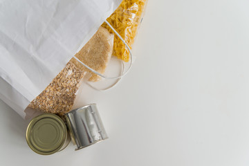Various canned food and raw cereal grains on a table with copy space