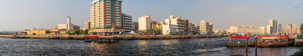 Fototapeta na wymiar Dubai Creek panorama with river, traditional taxi boats and buildings, United Arab Emirates.