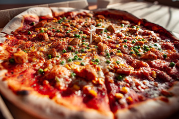 Hot tasty pizza ready to eat. Pizza in a cardboard box against a sunny background. Pizza delivery. Pizza menu.