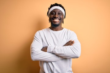 Young african american man doing sport wearing sportswer over isolated yellow background happy face smiling with crossed arms looking at the camera. Positive person.