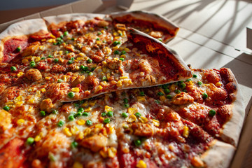 Hot tasty pizza ready to eat. Pizza in a cardboard box against a sunny background. Pizza delivery. Pizza menu.