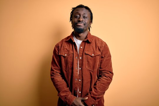 Young handsome african american man wearing casual jacket standing over yellow background depressed and worry for distress, crying angry and afraid. Sad expression.