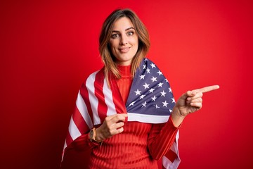 Young beautiful patriotic woman wearing united states flag celebrating inependence day very happy pointing with hand and finger to the side