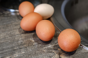 Chicken eggs lying on a wooden tabletop, top view, blurry background