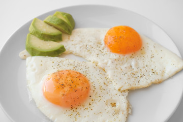Scrambled eggs with avocado and specialy on a white plate on a white background. Close-up, top view
