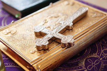 Golden gospel (holy bible) book and a silver cross on it. Russian eastern orthodox church.