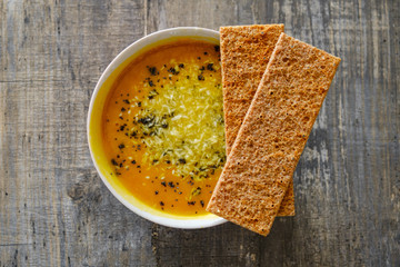 Pumpkin soup with bread on a wooden tabletop, top view
