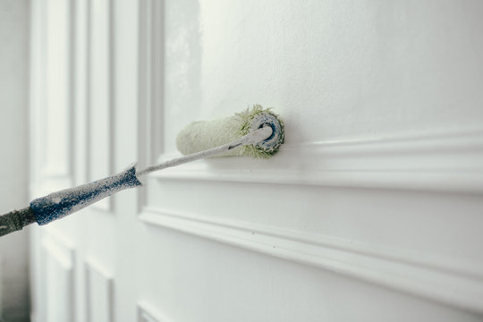 Close-up. Painting and repair of a decorative wall in white color with a construction roller. Construction tools