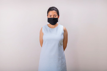 An Asian girl in blue tank top wears black mask