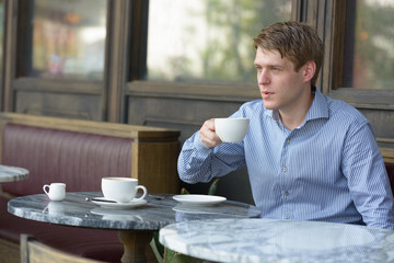 Young blond businessman thinking at the coffee shop outdoors
