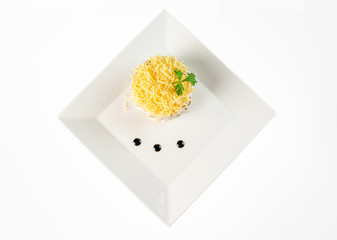 Round calad with grated cheese and sauce on a white square plate top view, on white background