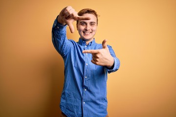 Young handsome redhead man wearing casual striped shirt over isolated yellow background smiling making frame with hands and fingers with happy face. Creativity and photography concept.