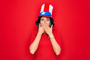 Young beautiful brunette woman wearing united states hat celebrating independence day shocked covering mouth with hands for mistake. Secret concept.