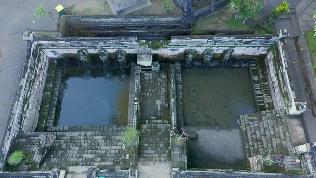 Early morning overlooking the pools of Goa Gajah Elephant Cave Temple in Ubud, Bali.  Aerial cinematic ascending shot in 4K