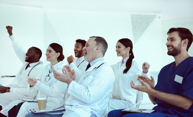 Cheerful doctors applauding during conference in clinic