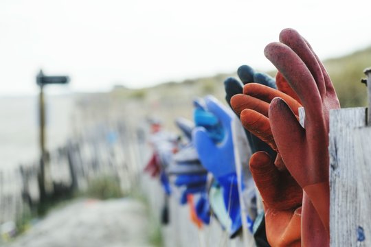Gloves On Fence Against Clear Sky