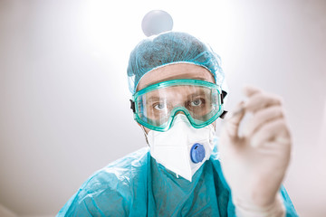 surgeon doctor in safety glasses and uniform works in the operating room and looks at the camera.