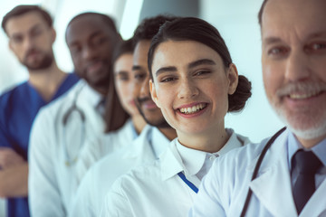 Cheerful female doctor standing with colleagues in clinic