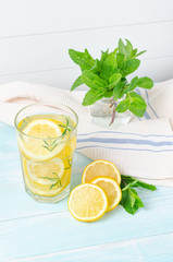 Preparation of the lemonade drink. Lemonade in the jug and lemons with rosemary on the table outdoor.