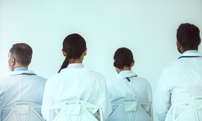 Group of medical workers sitting in front of white wall