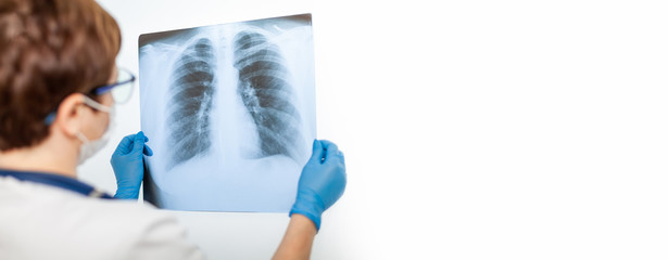 A female doctor examines an X-ray of a patient s lung infected with covid-19 coronavirus,...