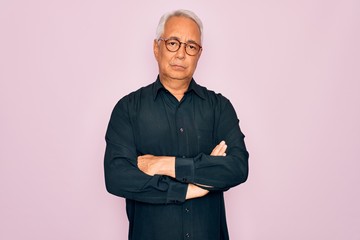 Middle age senior grey-haired handsome man wearing glasses and elegant shirt skeptic and nervous, disapproving expression on face with crossed arms. Negative person.