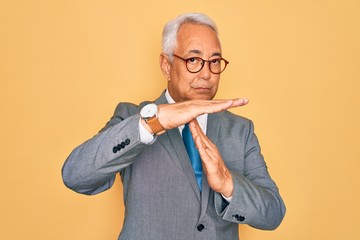 Middle age senior grey-haired handsome business man wearing glasses over yellow background Doing...