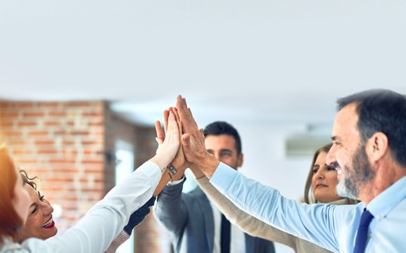 Group of business workers standing with hands together highing five at the office