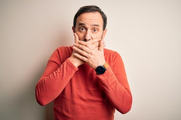 Middle age hoary man wearing casual orange sweater standing over isolated white background shocked covering mouth with hands for mistake. Secret concept.