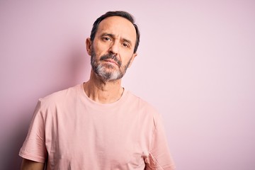 Middle age hoary man wearing casual t-shirt standing over isolated pink background Relaxed with...