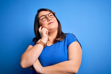 Fototapeta na wymiar Beautiful brunette plus size woman wearing casual t-shirt over isolated blue background with hand on chin thinking about question, pensive expression. Smiling with thoughtful face. Doubt concept.