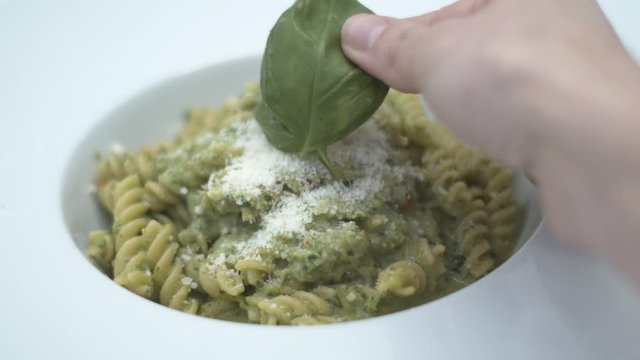 Mettere del basilico su pasta integrale al sugo di prezzemolo e parmigiano reggiano