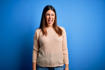 Young beautiful woman wearing casual sweater over blue background winking looking at the camera with sexy expression, cheerful and happy face.