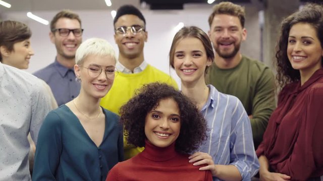 Portrait of successful group of business people at modern office. Happy businessmen and satisfied businesswomen standing together at creative office and looking at camera. Casual multiethnic group.