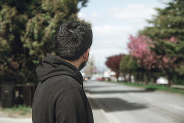 young man with a mask crossing a street in the city