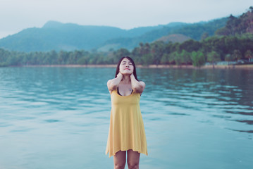 Happy asian woman standing with hands on head at the sea,Enjoying in Nature,Freedom concept