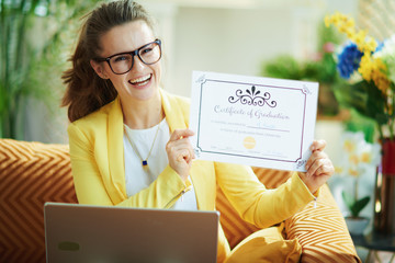 happy female with laptop showing certificate of graduation
