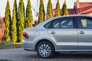 Back part of the car parked near the garage on the background of garden.