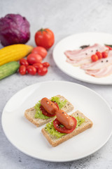 Fototapeta na wymiar Sausage with tomatoes, salad and two sets of bread on a white plate.