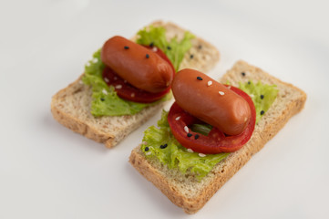 Fototapeta na wymiar Sausage with tomatoes, salad and two sets of bread on a white plate.