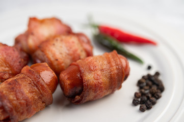 Sausage wrapped pork belly on a white plate.