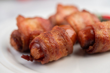 Sausage wrapped pork belly on a white plate.