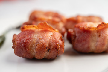 Sausage wrapped pork belly on a white plate.